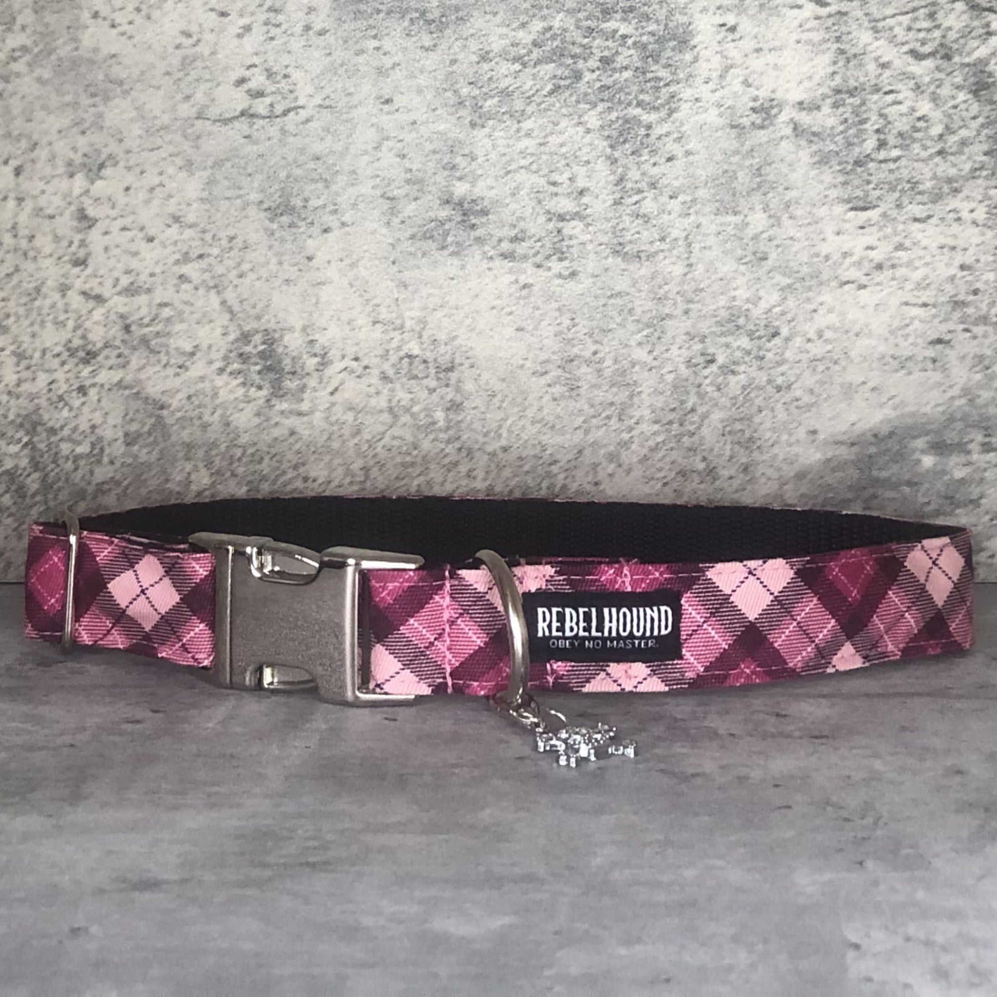 Pink plaid dog collar with metal buckle on a gray surface